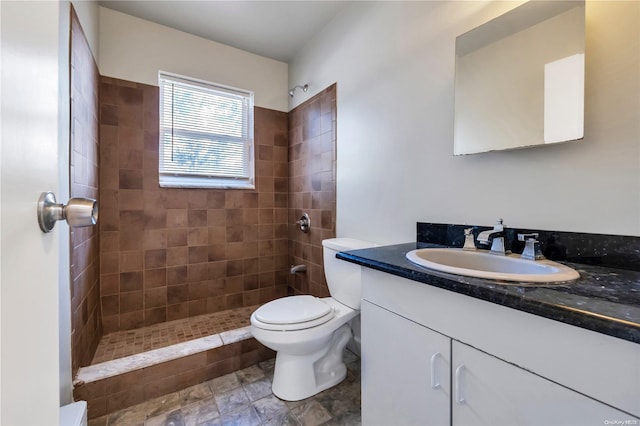 bathroom featuring vanity, toilet, and a tile shower