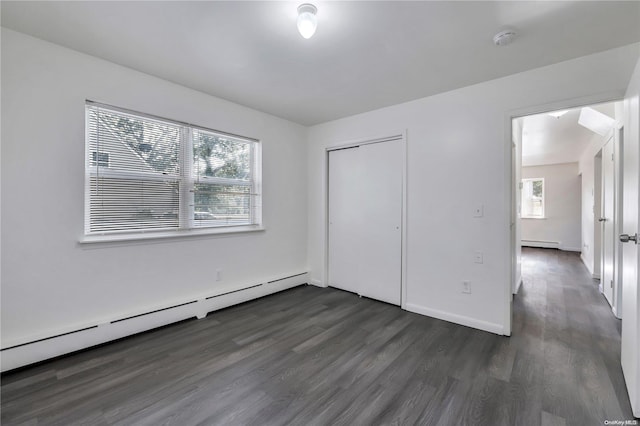 unfurnished bedroom with baseboard heating, a closet, and dark hardwood / wood-style floors