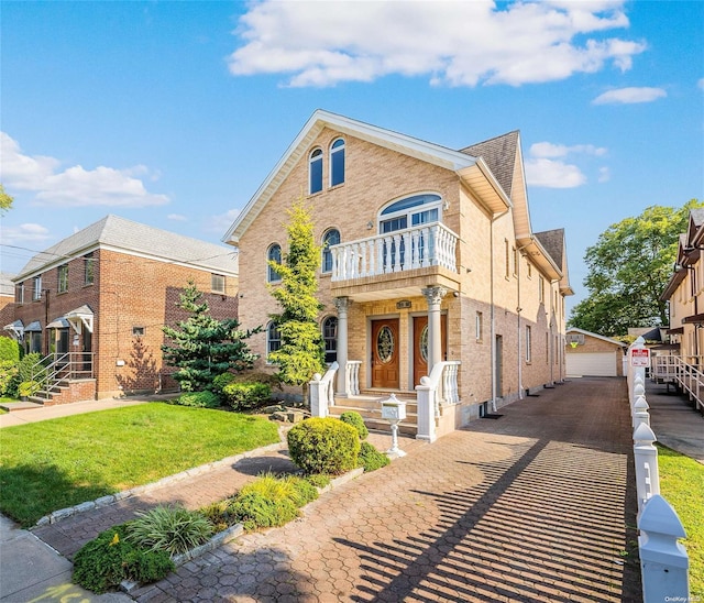 view of front of house with a balcony, a front lawn, an outdoor structure, and a garage