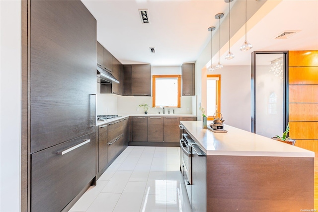 kitchen with sink, light tile patterned floors, pendant lighting, and stainless steel gas stovetop