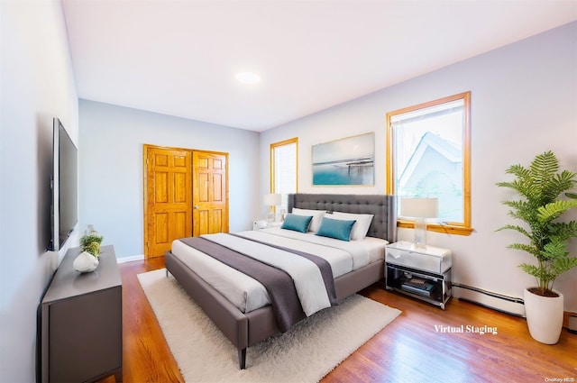 bedroom with a baseboard radiator and hardwood / wood-style flooring