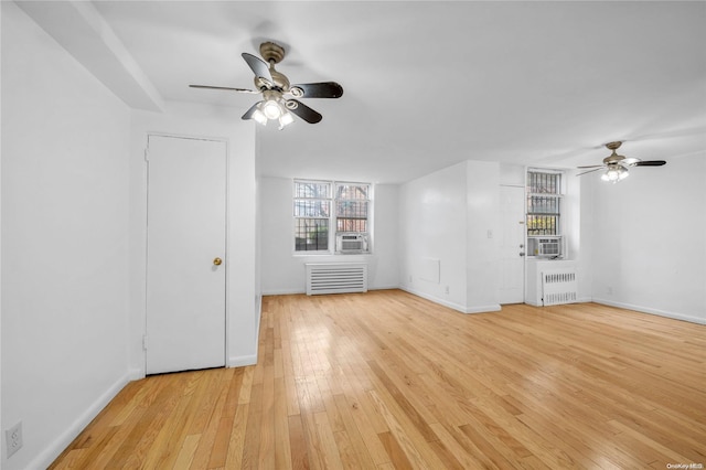 unfurnished living room with ceiling fan, radiator heating unit, cooling unit, and light hardwood / wood-style flooring