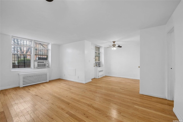 unfurnished living room with radiator, ceiling fan, cooling unit, and light wood-type flooring