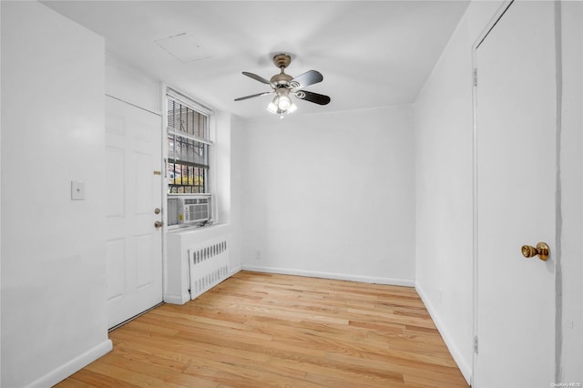 unfurnished room featuring ceiling fan, radiator heating unit, cooling unit, and light hardwood / wood-style floors