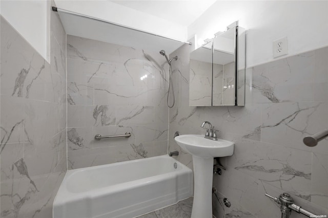 bathroom featuring tiled shower / bath combo, tile walls, and sink