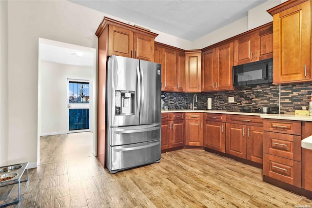 kitchen featuring tasteful backsplash, stainless steel fridge with ice dispenser, light hardwood / wood-style flooring, and sink