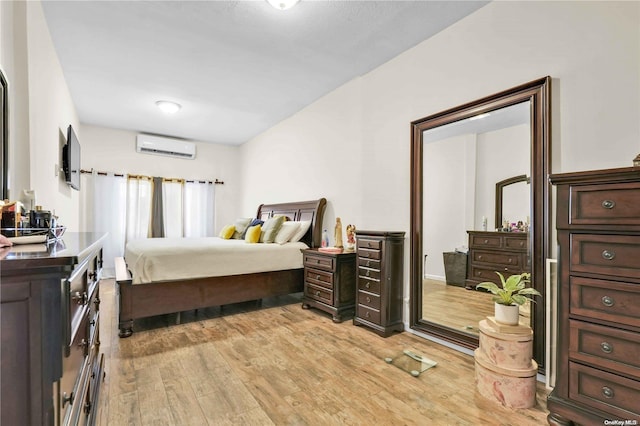 bedroom with a wall mounted AC and light hardwood / wood-style flooring