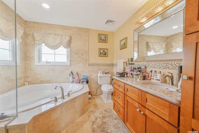 bathroom featuring vanity, tile patterned floors, toilet, tile walls, and tiled tub