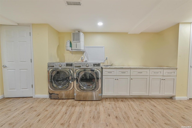 washroom with light hardwood / wood-style floors, cabinets, and washing machine and clothes dryer