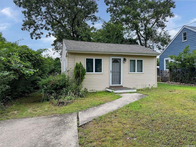 bungalow with roof with shingles and a front lawn