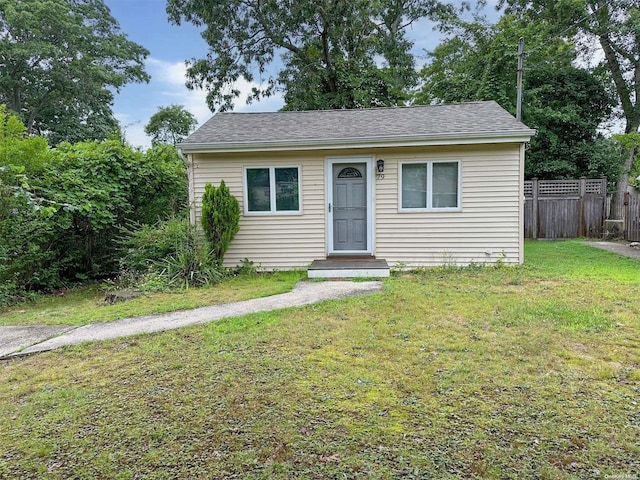 bungalow-style home featuring a front yard, roof with shingles, and fence