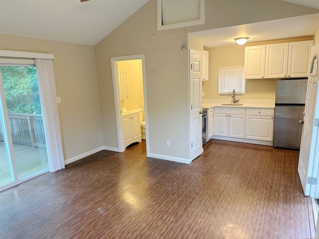 kitchen featuring stainless steel appliances, a sink, white cabinets, vaulted ceiling, and light countertops