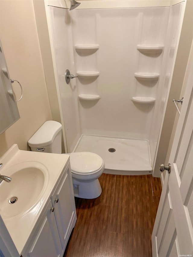 bathroom with a stall shower, vanity, toilet, and wood finished floors