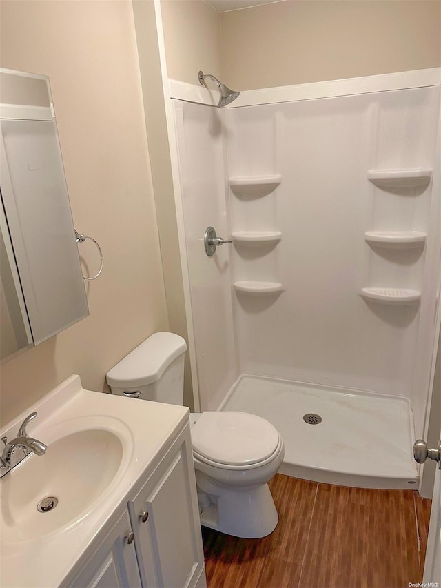 full bathroom featuring toilet, a stall shower, wood finished floors, and vanity