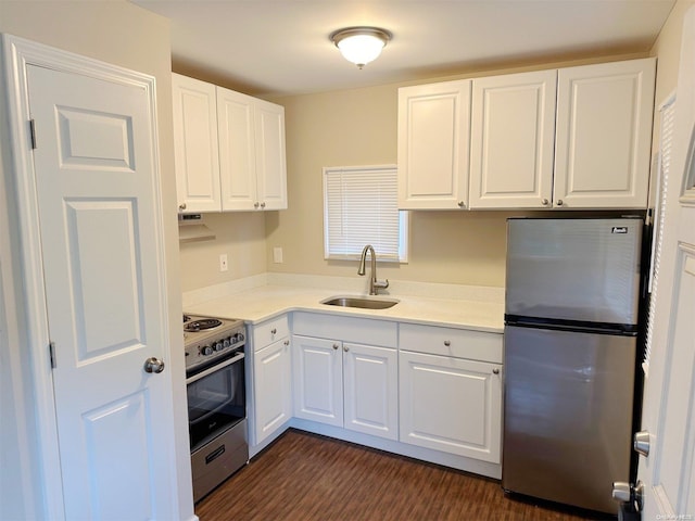 kitchen featuring stainless steel appliances, light countertops, dark wood-type flooring, white cabinets, and a sink