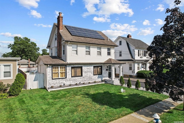 view of front of property with solar panels and a front yard