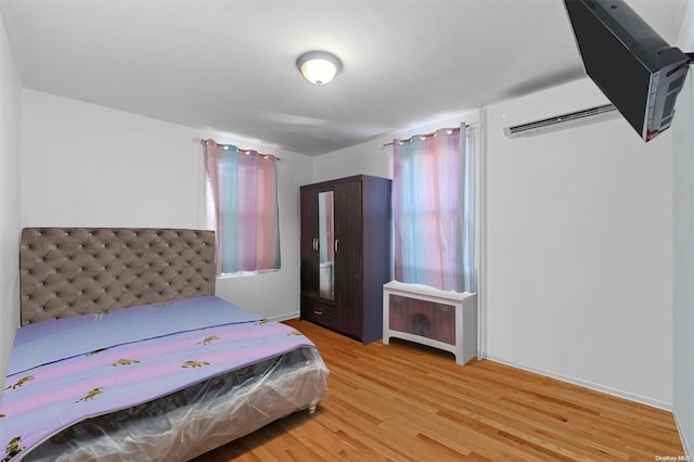 bedroom with wood-type flooring and an AC wall unit