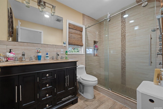 bathroom featuring walk in shower, toilet, decorative backsplash, vanity, and tile walls