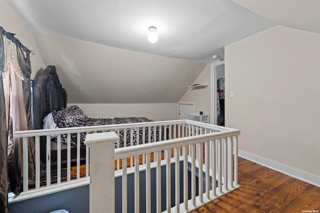 bedroom featuring a crib, wood-type flooring, and lofted ceiling