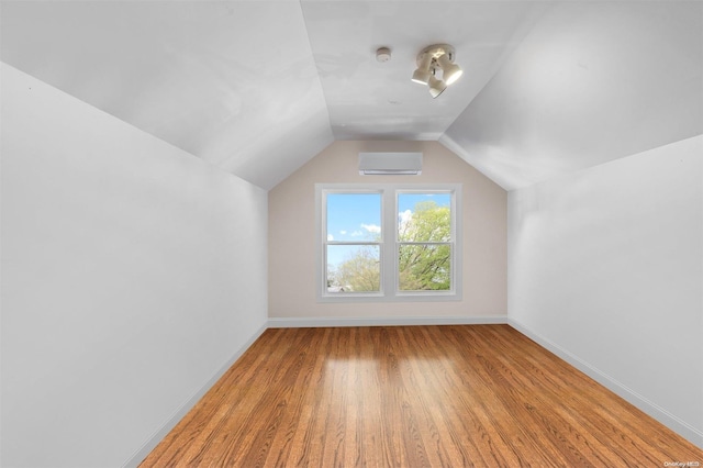 bonus room featuring a wall mounted air conditioner, wood-type flooring, and vaulted ceiling