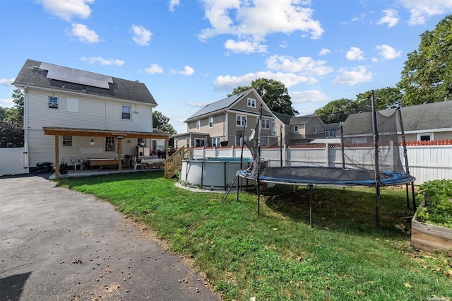 view of swimming pool featuring a yard, a trampoline, and a patio