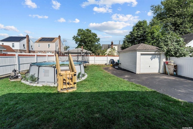 view of yard with an outbuilding, a fenced in pool, and a garage