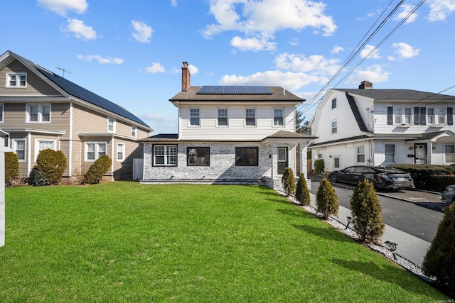 view of front of home featuring solar panels, a front lawn, and a chimney