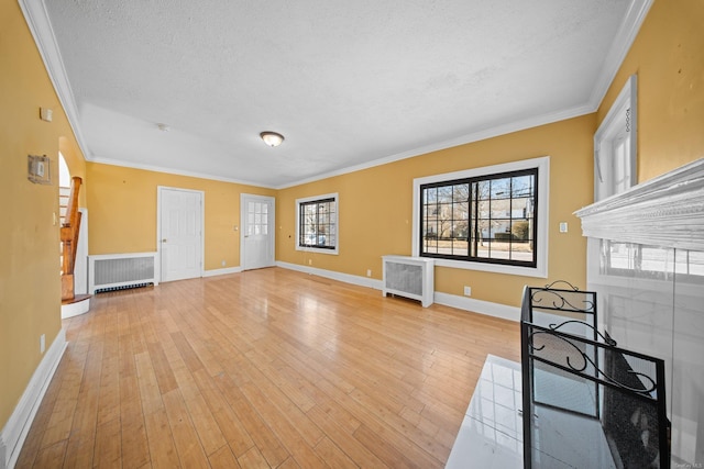 unfurnished living room featuring baseboards, radiator heating unit, ornamental molding, a textured ceiling, and light wood-type flooring