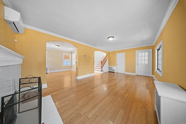 living area with arched walkways, light wood-type flooring, stairway, and a wall unit AC