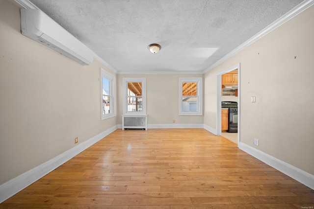 unfurnished living room with baseboards, light wood-style floors, an AC wall unit, radiator, and crown molding