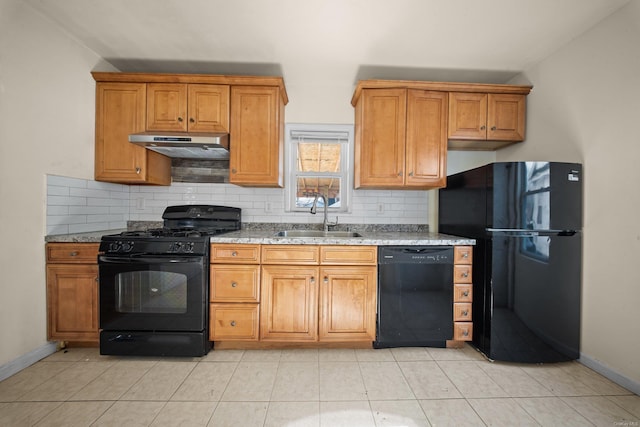 kitchen with decorative backsplash, brown cabinetry, a sink, under cabinet range hood, and black appliances