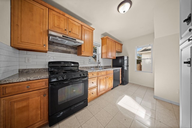 kitchen with light tile patterned flooring, under cabinet range hood, a sink, black appliances, and tasteful backsplash