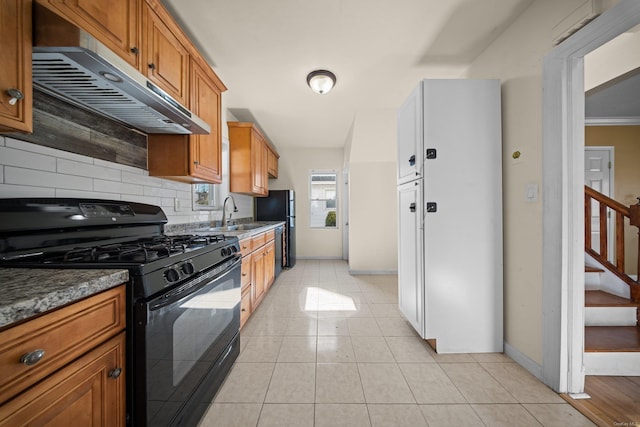 kitchen featuring decorative backsplash, brown cabinetry, light tile patterned flooring, under cabinet range hood, and black appliances