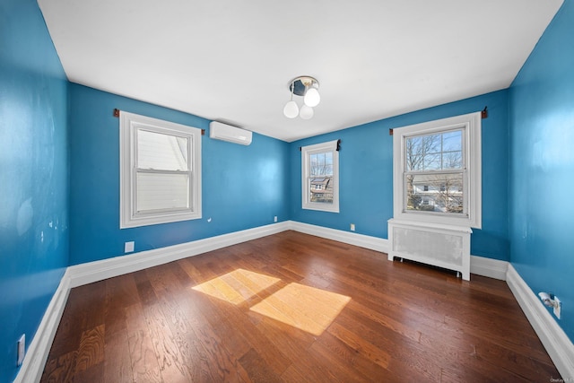 empty room featuring radiator heating unit, baseboards, an AC wall unit, and wood finished floors