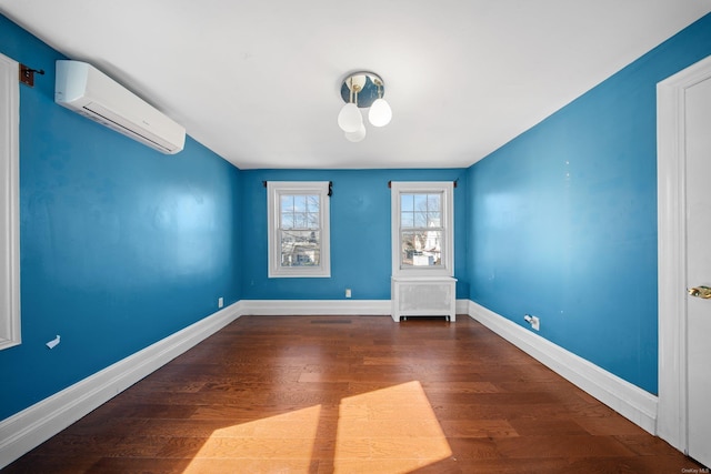 spare room with baseboards, an AC wall unit, and wood finished floors