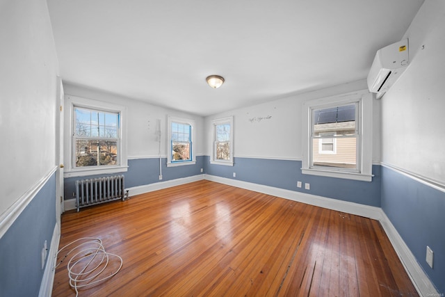 spare room featuring radiator heating unit, wood-type flooring, and baseboards