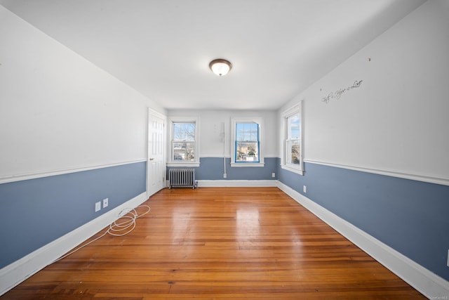 empty room featuring radiator, baseboards, and wood finished floors