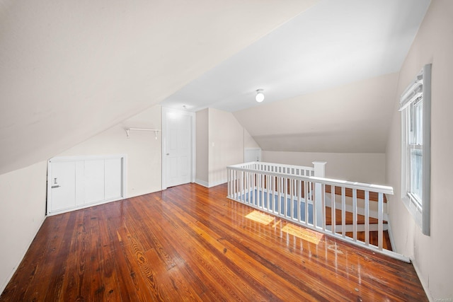 additional living space with wood-type flooring and vaulted ceiling