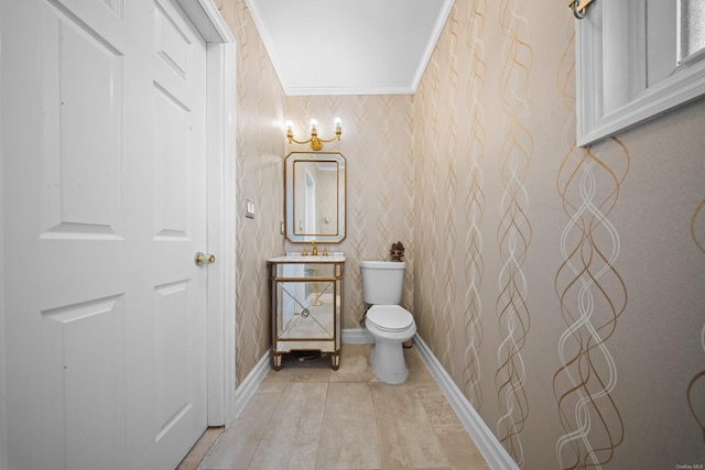 bathroom featuring crown molding, toilet, vanity, baseboards, and wallpapered walls