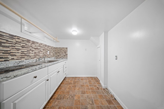 kitchen with baseboards, white cabinets, decorative backsplash, black electric cooktop, and a sink