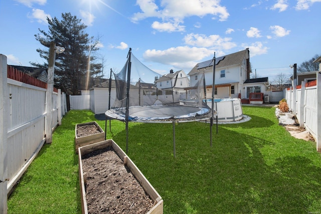 view of yard featuring a trampoline, a fenced backyard, a vegetable garden, and a fenced in pool