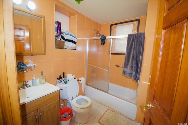 full bathroom featuring vanity, tile patterned floors, bath / shower combo with glass door, toilet, and tile walls