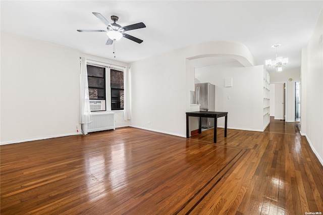 unfurnished living room featuring radiator heating unit, dark wood-type flooring, and ceiling fan with notable chandelier