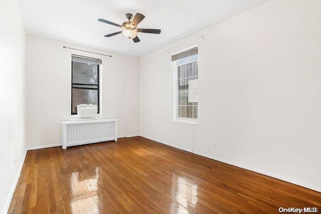 unfurnished room featuring hardwood / wood-style floors, ceiling fan, and radiator