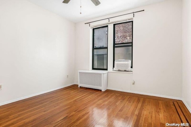 spare room with ceiling fan, radiator heating unit, cooling unit, and hardwood / wood-style flooring