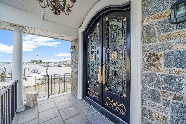 property entrance with covered porch and french doors