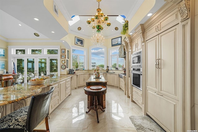 kitchen with a kitchen bar, crown molding, light stone counters, stainless steel appliances, and a chandelier