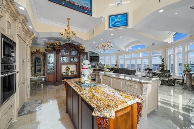 kitchen featuring light stone countertops, a kitchen island, cream cabinetry, a chandelier, and black oven