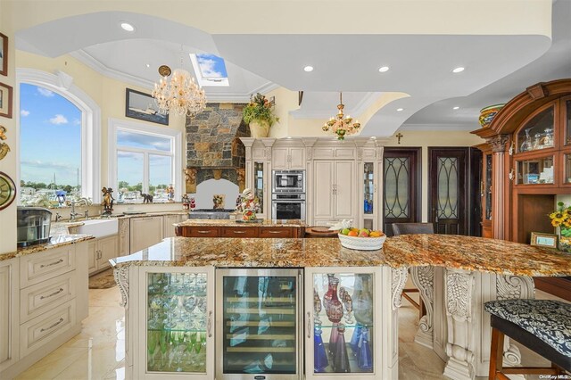 kitchen with light stone countertops, stainless steel appliances, a chandelier, a center island, and wine cooler