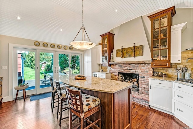 15405 Main Rd, Mattituck, NY 11952 - kitchen featuring a center island, lofted ceiling, dark wood-style flooring, backsplash, and a fireplace